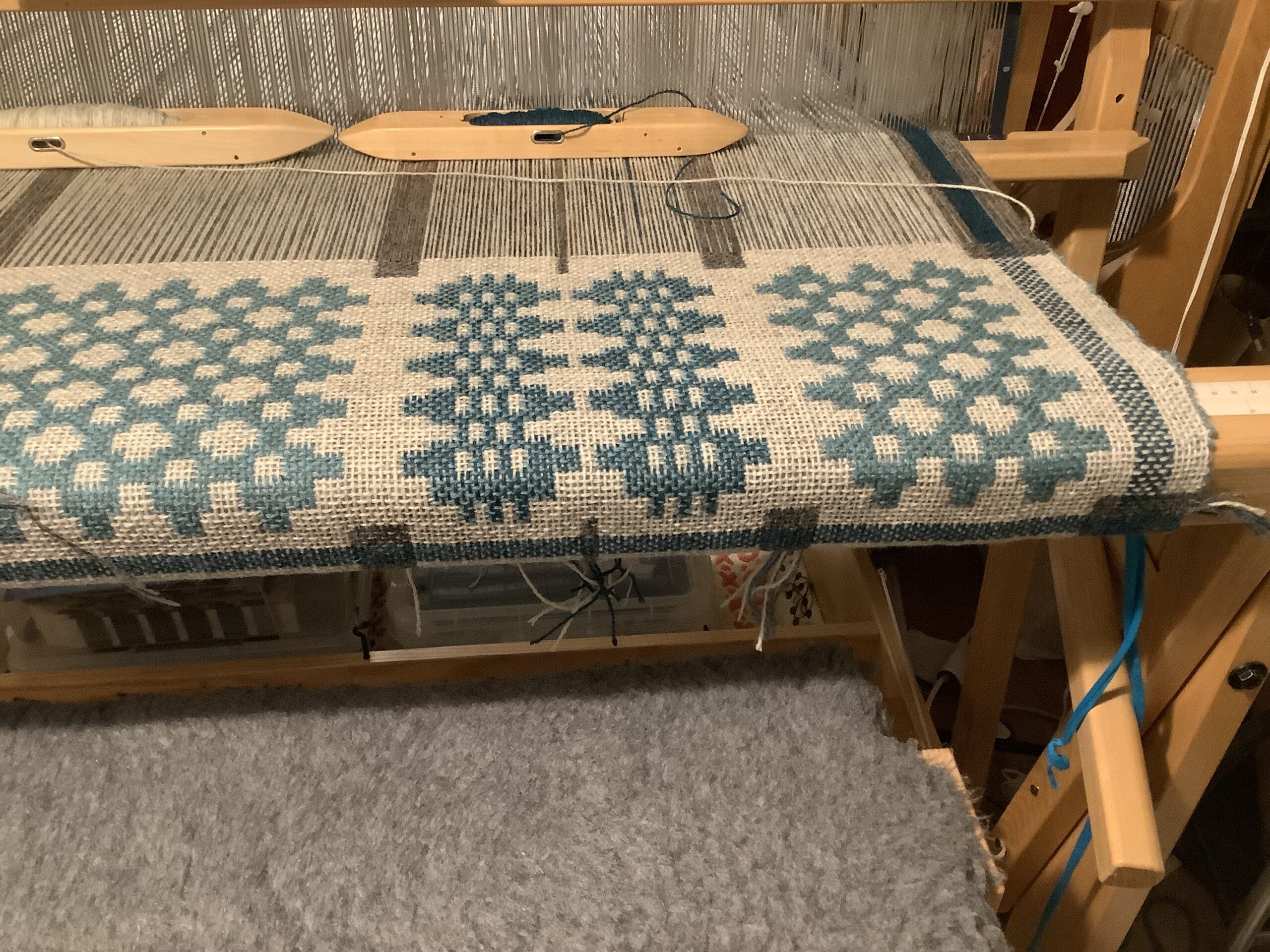 A section of a blanket being woven on a floor loom.