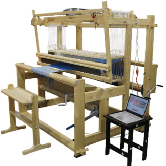 A Toika Eeva loom, made of wood, with a bench and a computer on a low table alongside.
