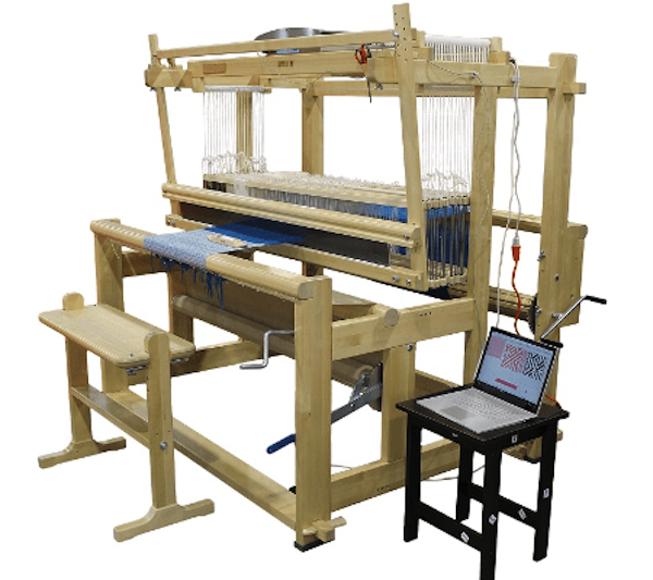 Toika Eeva ES Computer Controlled Loom A Toika Eeva loom, made of wood, with a bench and a computer on a low table alongside.
